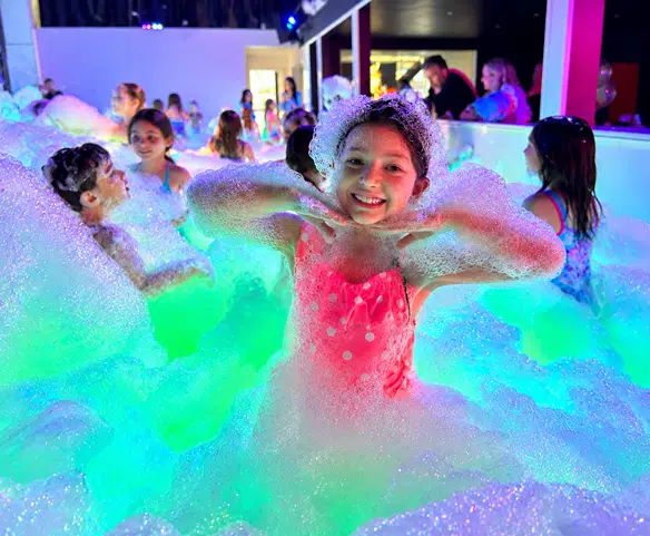 Enfants profitant d’une fête en mousse Wow Foam avec musique et éclairage intérieurs