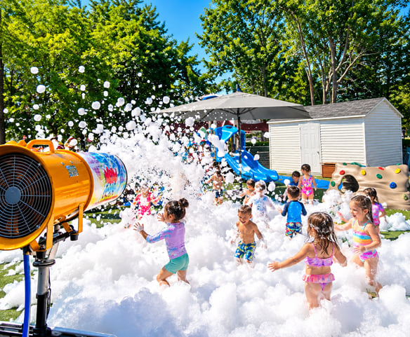 Enfants jouant dans une fête en mousse à la garderie avec un canon à mousse Wow Foam