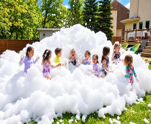 Enfants jouant dans une fête en mousse à domicile avec un canon à mousse